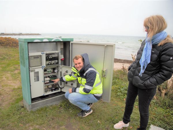 Servicechef Janus Brosbøl og salgsingeniør Tine Undén, MJK Automation, viser styre- og overvågningsenhed MμConnect istyreskabet til et af overløbsbygværkerne på en vindblæst strand i Snekkersten.